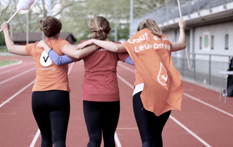 Three young women cheer on the tartan track.