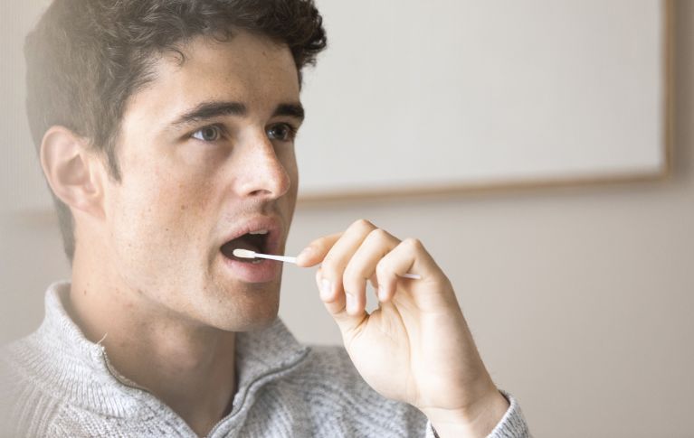 A young man takes a cheek swab for blood stem cell donation.